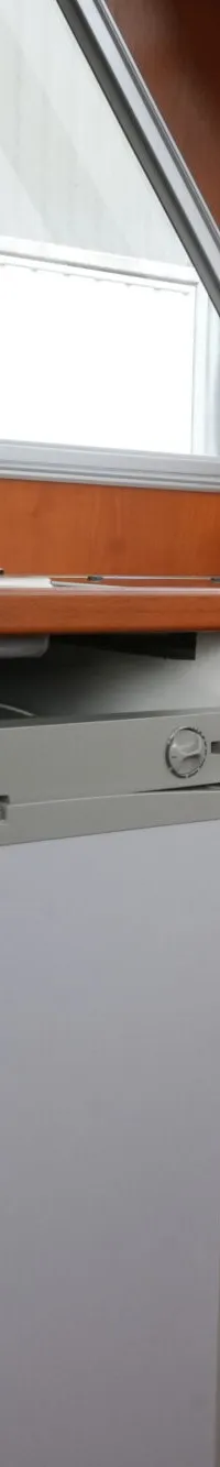 Een interieur van een boot met een houten afwerking, een Dometic koelkast, een gootsteen en ramen met gordijnen.
