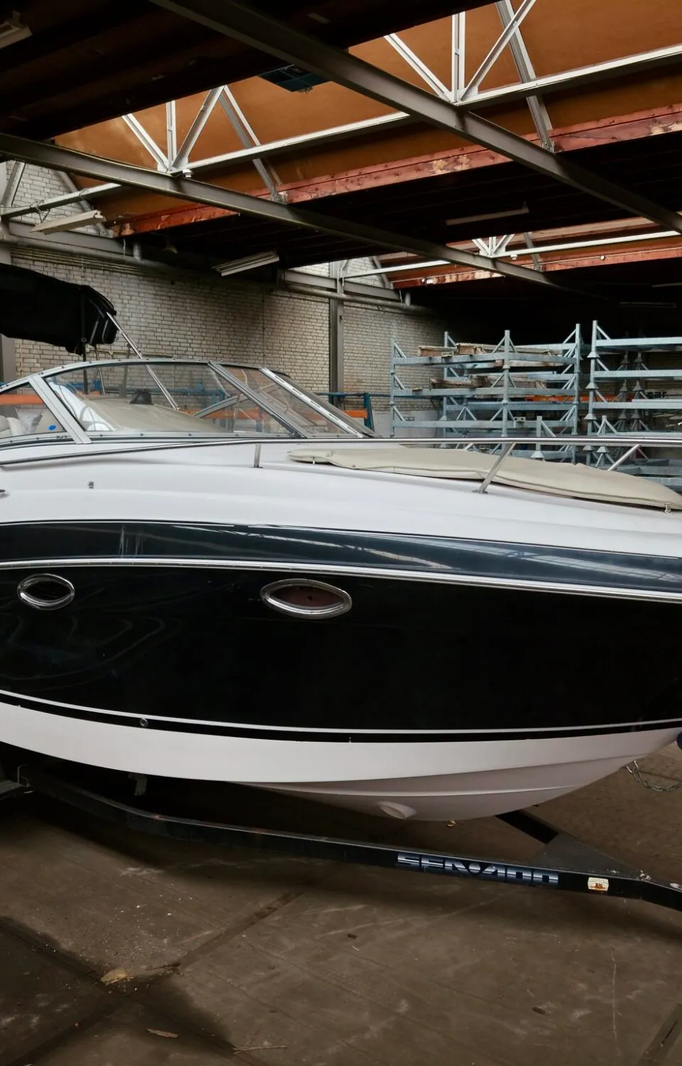 Een witte en donkerblauwe boot met de naam "Angelique" op een trailer in een loods. — Four Winns Four Winns 258 Vista