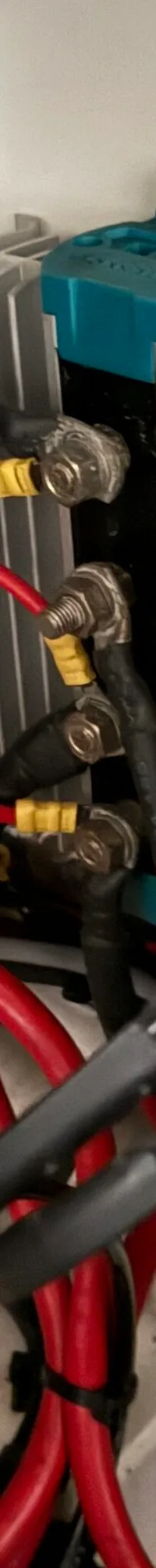 Een detailfoto van een wirwar aan rode en zwarte kabels, aangesloten op diverse elektrische componenten.