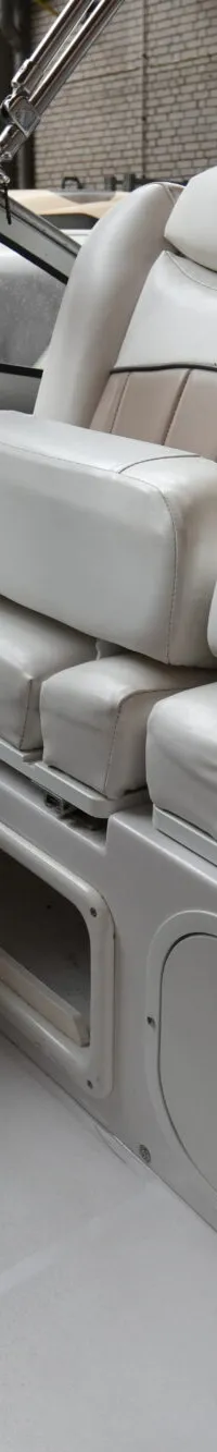 De foto toont het interieur van een boot met twee beige en bruine stoelen, een stuurwiel en een waarschuwingssticker.