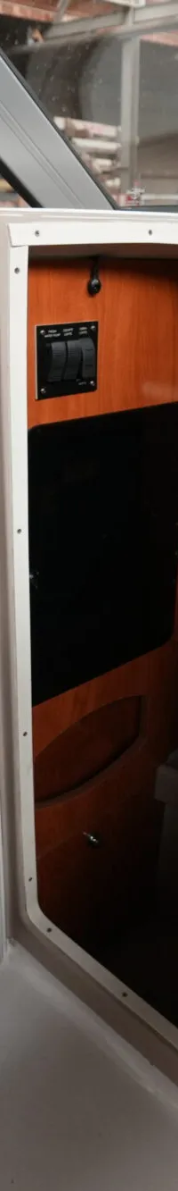 Een openstaande deur met een waarschuwingssticker en een hor, die toegang geeft tot een kajuit met houten interieur en…