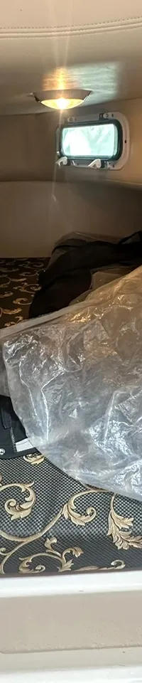 De foto toont het interieur van een boot met een kombuis aan de linkerkant en een zithoek aan de rechterkant.