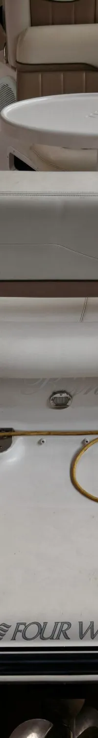 De achterkant van een witte boot met beige bekleding, een tafel en een opgerolde gele kabel is zichtbaar.