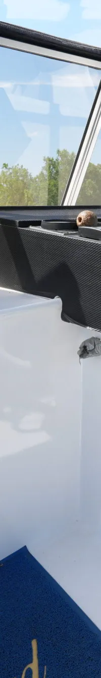 Een witte stuurstand met een wit stuurwiel en een zwarte stuurstoel is zichtbaar, met een open luik naar een lagere stuurhut.