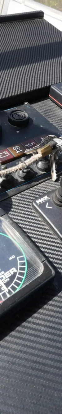 Een detailfoto toont het dashboard van een boot met diverse meters, schakelaars, een gashendel, een thruster joystick en…