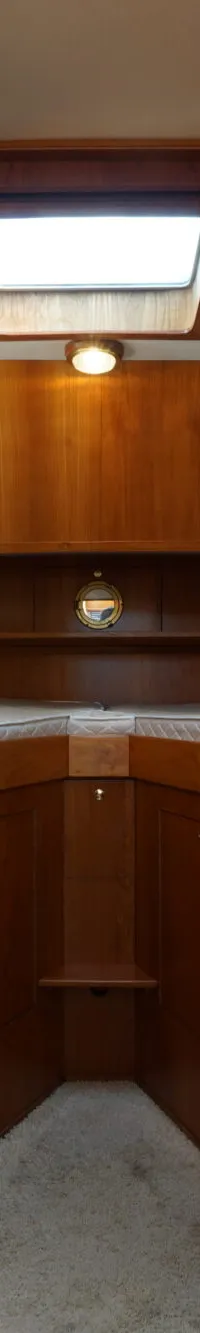 Een interieur van een boot met houten wanden, een bruine bank, twee klokken, twee decoratieve borden en een doorgang naar…