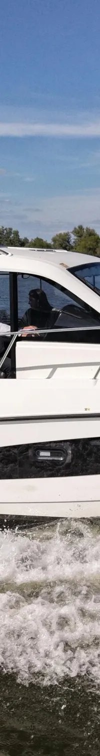 Een witte motorboot met de naam "LEVANTO" en registratie "5-YF-634" vaart over water, bestuurd door een persoon.