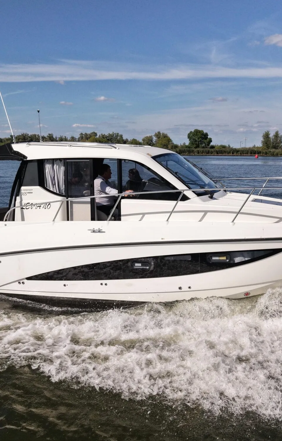 Een witte motorboot met de naam "LEVANTO" en registratie "5-YF-634" vaart over water, bestuurd door een persoon.