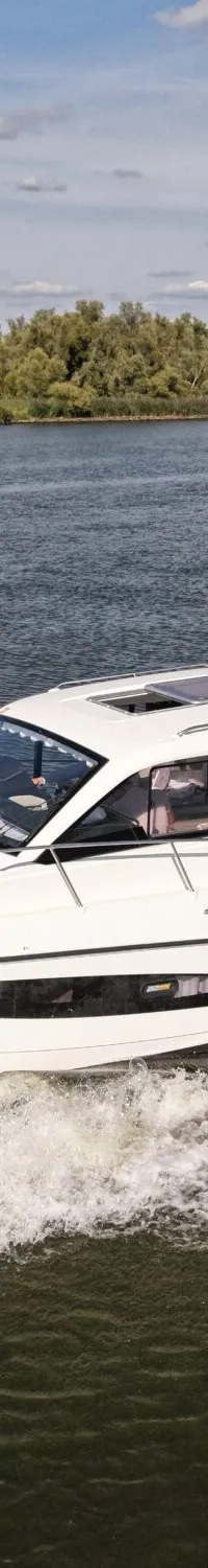 Een witte motorboot met registratienummer 5-VF-634 vaart op het water, met een persoon aan boord en bomen op de achtergrond.