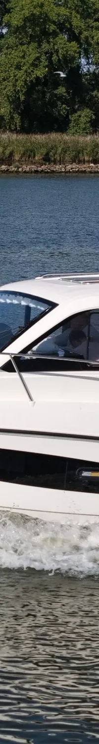 Een witte motorboot met de registratie "5-YF-634" vaart over water, omringd door groen aan de oever.