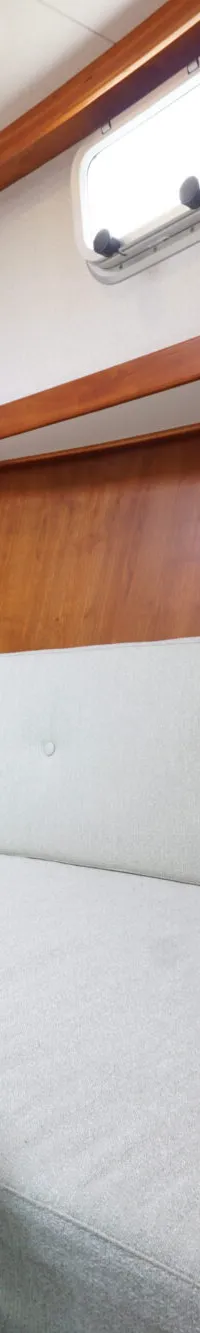 Een kajuit met houten wanden, een lichtgroene bank met kussens en een houten tafel. — Vedette Vedette 8.80 OK Spiegeldeur