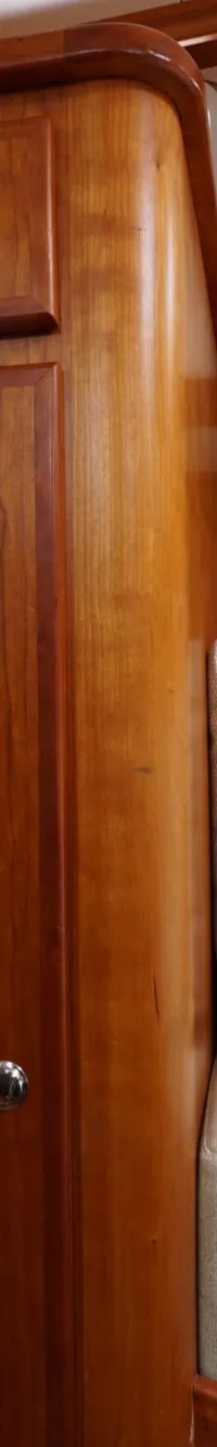 De foto toont een houten interieur met een bankje met kussens, een kastje en een deur.
