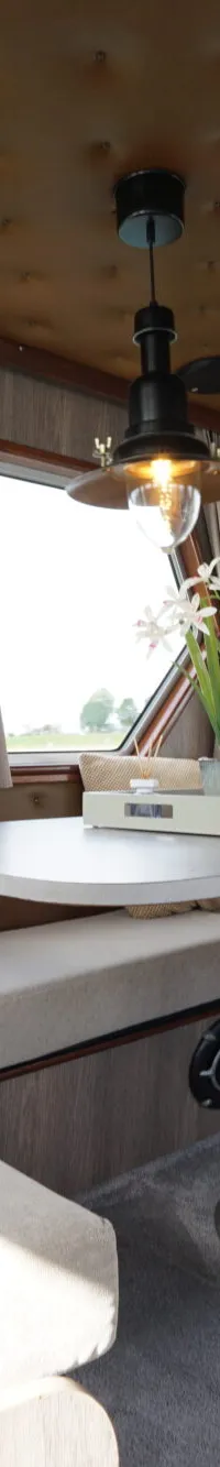 De foto toont het interieur van een boot met een zithoek, tafel, ramen en een hanglamp. — Buijs Buijs Kruiser 10.80 OK