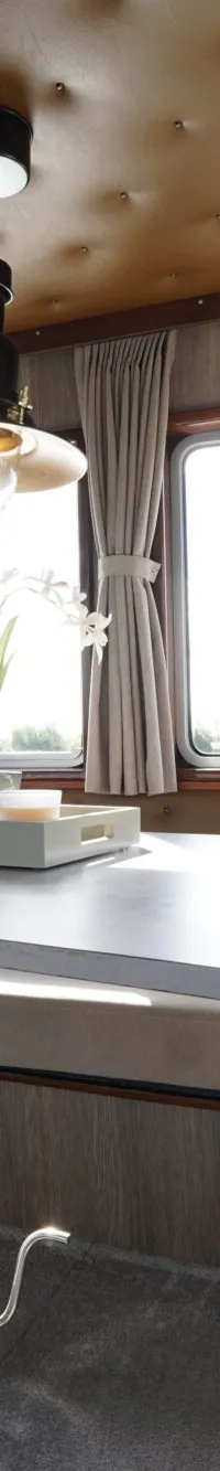 De foto toont het interieur van een boot met een zithoek, een tafel en ramen met gordijnen. — Buijs Buijs Kruiser 10.80 OK