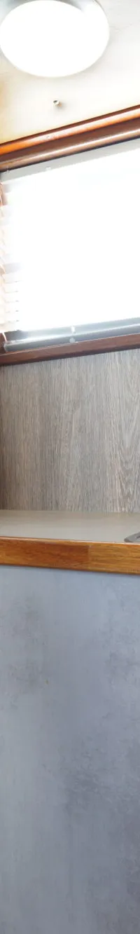Een compacte kombuis met een spoelbak, kraan, koelkast, opbergkasten en een raam.