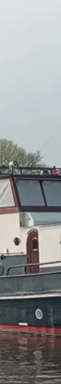 Een donkerblauwe boot met een witte opbouw en rode accenten ligt in het water, met "JAN ABELS" op de boeg.