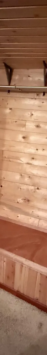 Een houten interieur met een wasmachine, een patrijspoort met blauw licht, een kledingrek en een verhoogd houten platform.