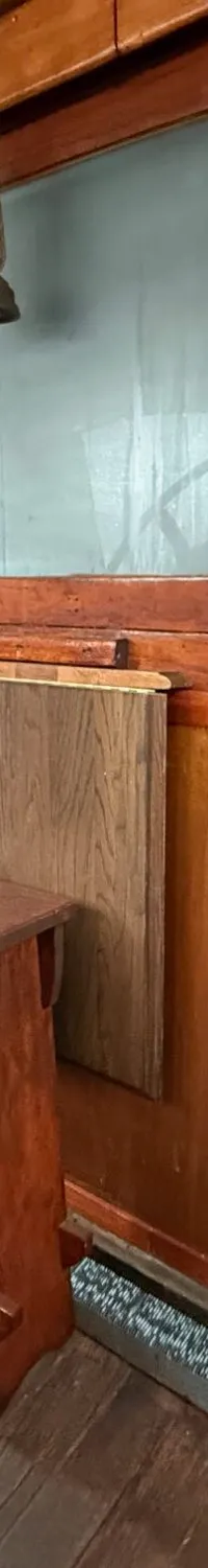 Een houten stuurwiel, een houten krukje, een olielamp en een geel bord met instructies zijn zichtbaar in de kajuit.