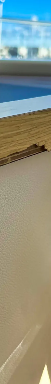 Een close-up van een bootinterieur met een houten rand, een wit getextureerd oppervlak en een zwarte gashendel met knoppen.