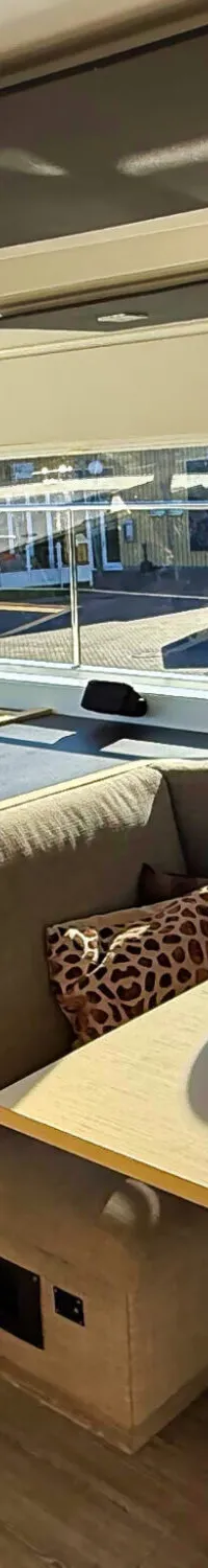 De foto toont het interieur van een boot met een kombuis, zithoek, tafel en grote ramen.