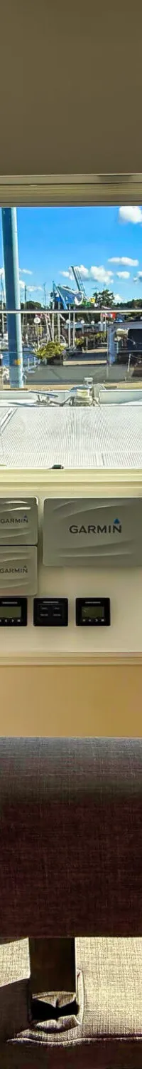 De foto toont het interieur van een boot met een stuurwiel, Garmin-schermen en een zitbank, met uitzicht op een jachthaven.