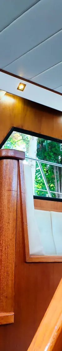 De foto toont het interieur van een boot met veel houtwerk, ramen en een wit plafond.