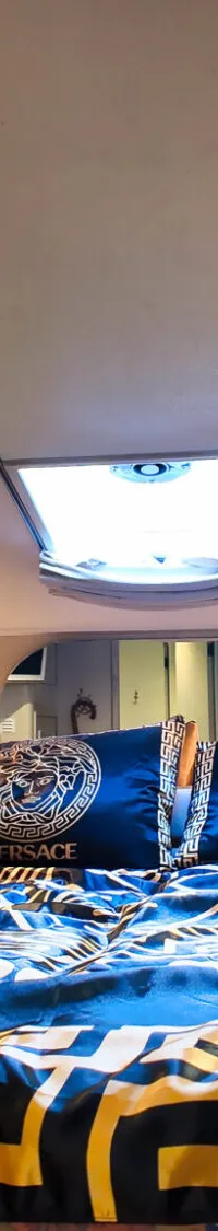 Een kajuit met een tweepersoonsbed, een dakraam, patrijspoorten en een televisie.