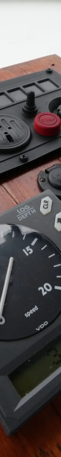 Een houten dashboard met diverse instrumenten, waaronder een Yanmar toerenteller, een snelheidsmeter en een…