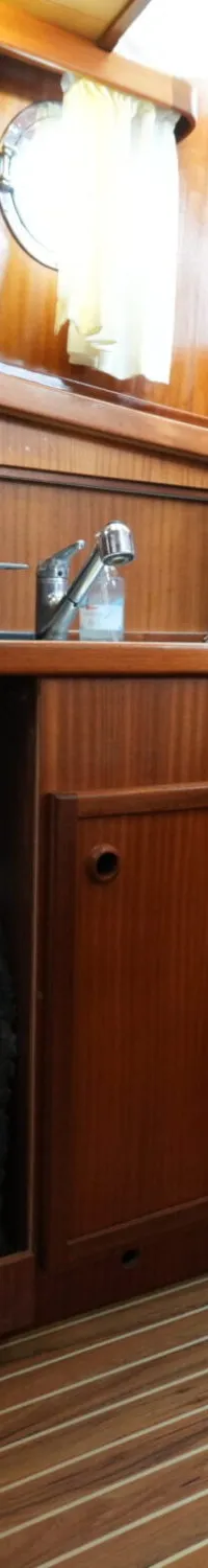 Een interieur van een boot met houten wanden, een wasmachine, een gootsteen, een koffiezetapparaat en een trap.