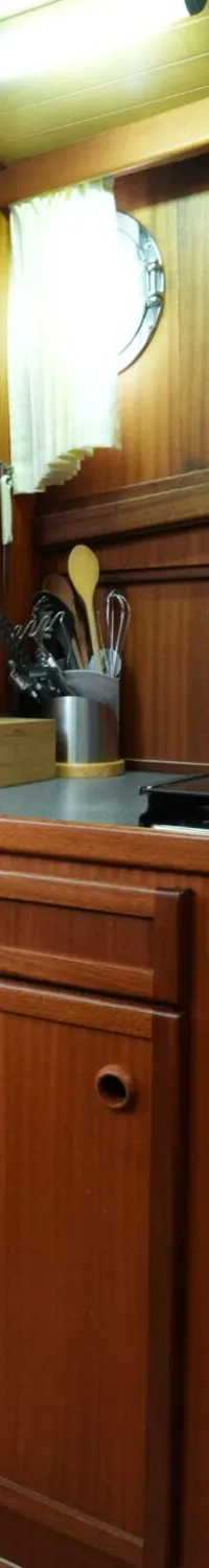 Een kombuis met houten kasten, een koelkast, een fornuis, een spoelbak en een patrijspoort.