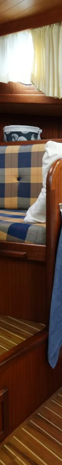 Een interieur van een boot met houten wanden en vloer, een geruite bank, een tafel, een tv, een patrijspoort en een…