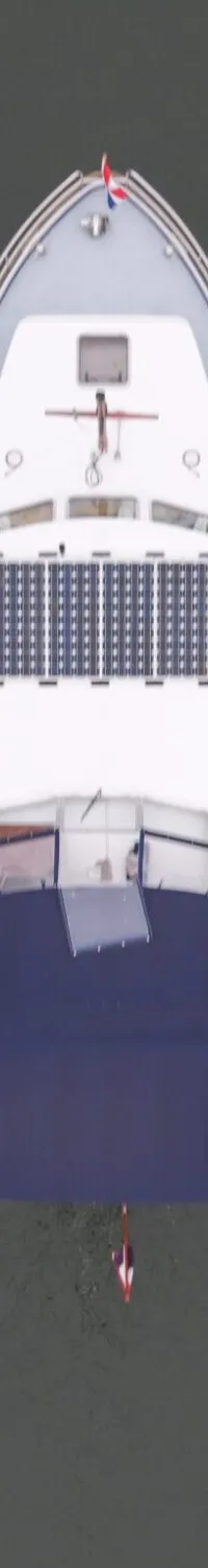 Een witte boot met een blauwe kap en zonnepanelen op het dak, vaart op grijs water. — Brandsma Brandsmavlet 10.50 AK Cabrio