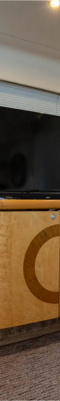 Een interieur van een boot met een houten kast, een televisie, een ijsemmer, een printer en een trap.