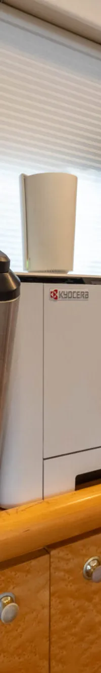 Een interieur van een boot met een ijsmachine, printer, flessen wijn, een boeddhabeeld en een trap.