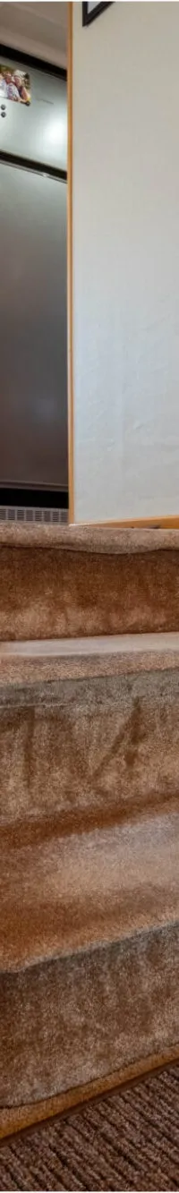 Een interieur van een boot met een gestoffeerde trap, een witte bank en een houten balustrade.