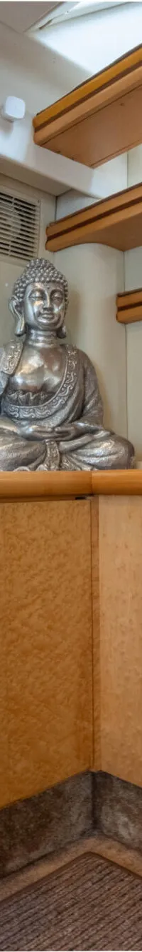 Een interieur van een boot met een trap, een televisie, een zilveren Boeddhabeeld en een lamp.