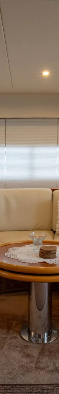 Een interieur van een boot met een crèmekleurige U-vormige bank, een ronde houten tafel en een tapijtvloer.