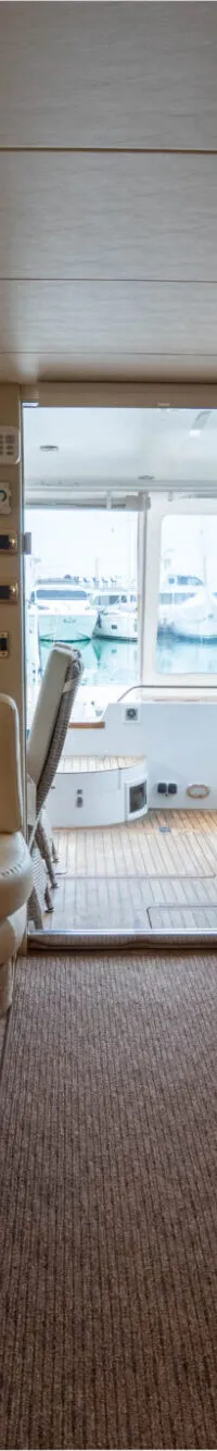 Een interieurfoto van een boot met een crèmekleurige bank, een houten salontafel, een tv en een houten kast.