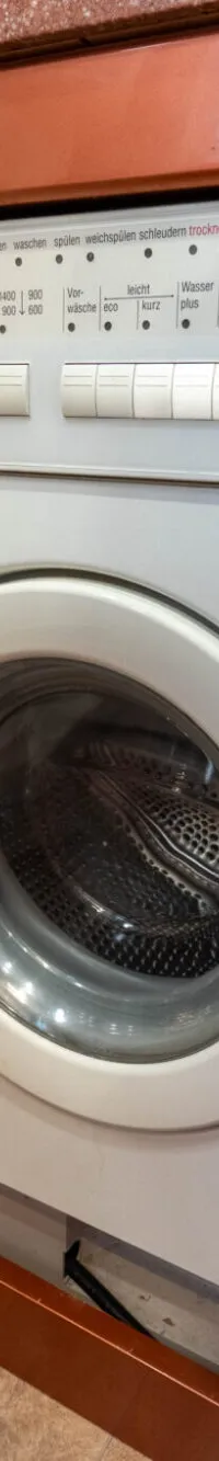 Een witte Bosch wasmachine met een ronde deur en bedieningspaneel is ingebouwd in een houten interieur.