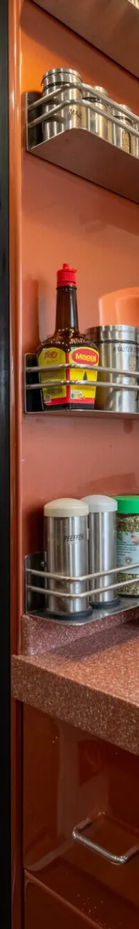 Een kombuis met een koelkast, kruidenrekken, een inductiekookplaat en een zithoek met een ronde bank.