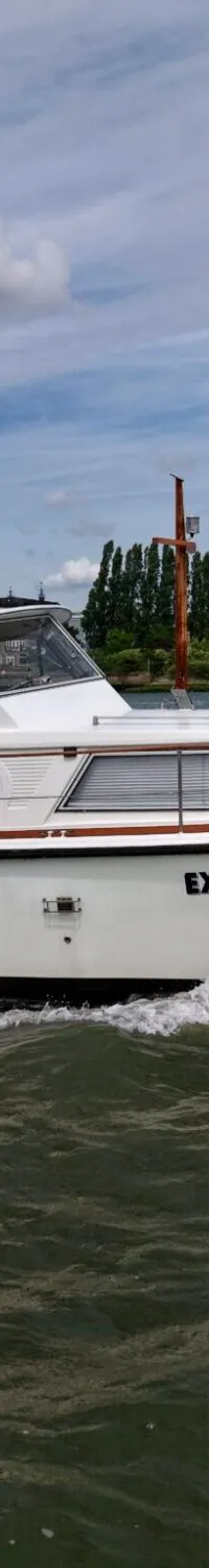 Een witte motorboot met de naam "EXPLORER" vaart op water, met een blauwe kap en registratienummer YD 22-77.