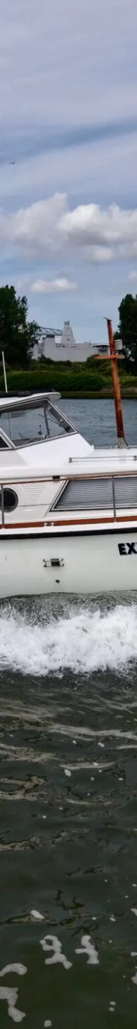 Een witte motorboot met de naam "EXPLORER" vaart op water, met een blauwe kap en registratienummer YD 22-77.