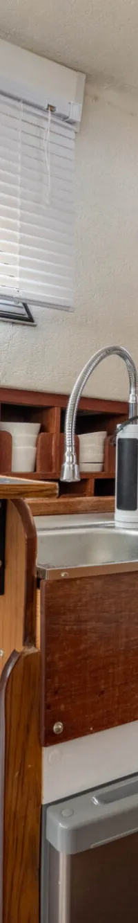 De foto toont een bootinterieur met een kombuis, inclusief een gootsteen, kookplaat, koelkast en opbergruimte.