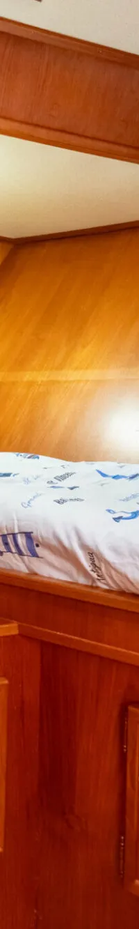 Een kajuit met twee stapelbedden, houten wanden en een plafondlamp. — Treffer Treffer Kruiser 13.50 VS