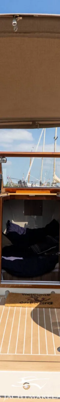 De foto toont de cockpit van een boot met twee beige stoelen, een houten stuurwiel en een bruine kap. — PTS PTS 26