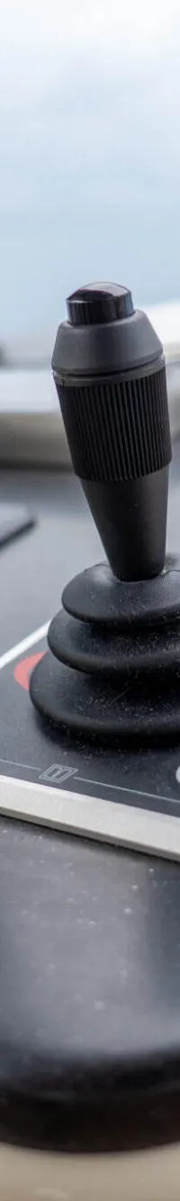 Een close-up van een zwart bedieningspaneel met een joystick, knoppen en een gele sleutelhanger.