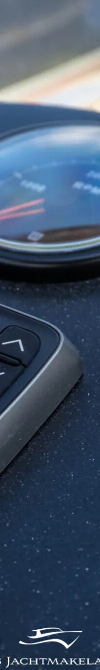 Een close-up van een donker dashboard met diverse meters, waaronder een Raymarine dieptemeter en een waterniveaumeter.