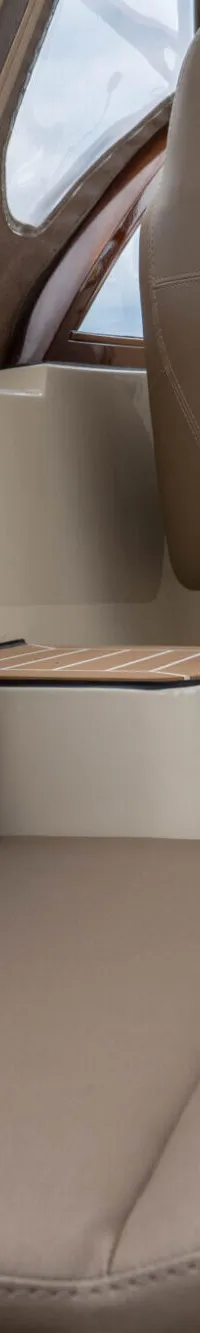 Twee beige bootstoelen met een "Statement Marine" logo op de rugleuning, en een kajuitingang met houten kozijnen.