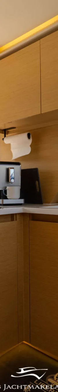 Een moderne kombuis met houten kasten, een aanrechtblad, een gootsteen, een kookplaat en een koffiezetapparaat.