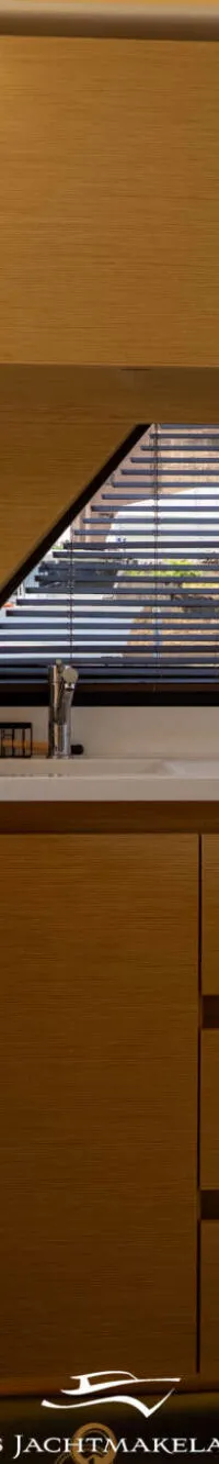 Een moderne kombuis met lichte houten kasten, een wit aanrechtblad, een kookplaat, een gootsteen en een koffiezetapparaat.